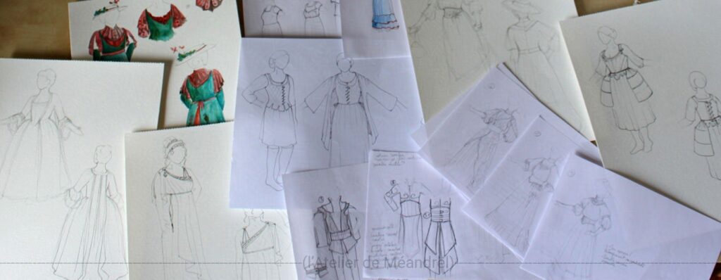 Photo de croquis de costumes étalés sur une table ; les silhouettes sont réalistes, dessinées d'après photos des personnes.