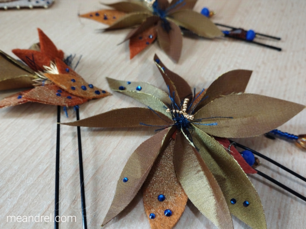 Trois épingles à cheveux, faites des mêmes fleurs que celles des épaules.