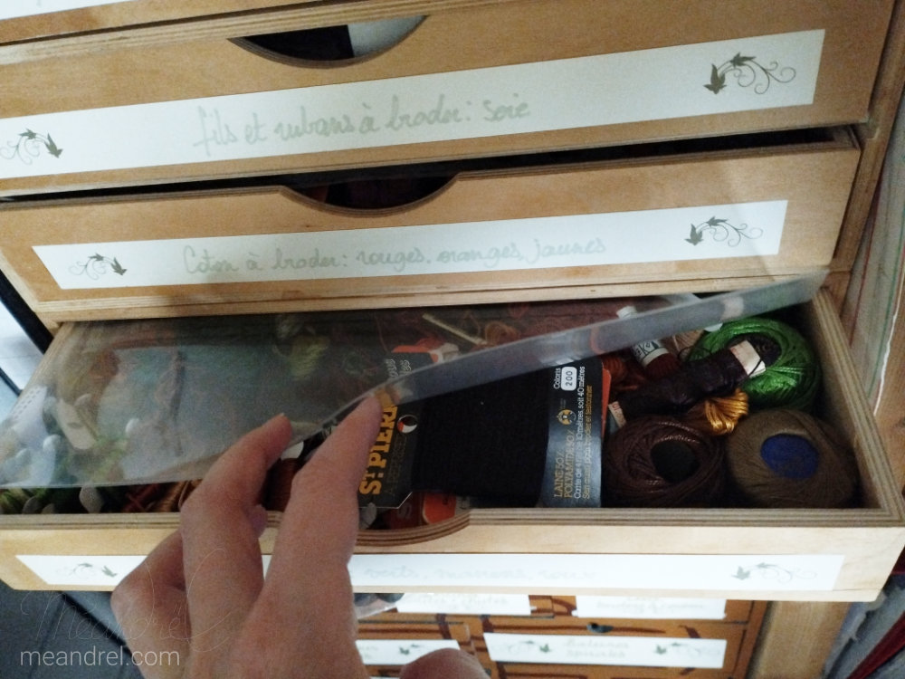 Un tiroir plein de cotons à broder, couvert d'une feuille plastique transparente.