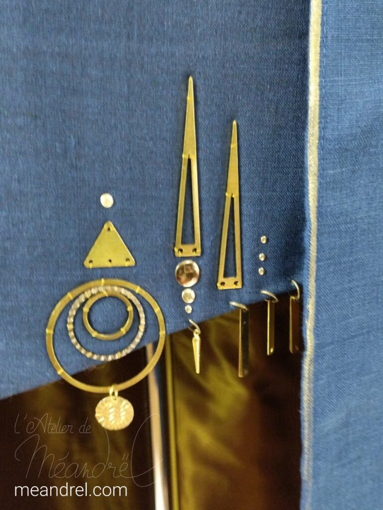 Photo de détail de cercles et triangles en laiton, cousus au bord bas du gilet.