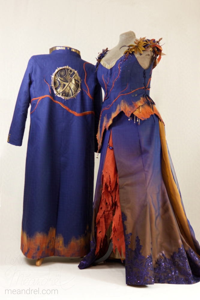 Photo de la tenue, de face, sur mannequin ; avec une deuxième mannequin, de dos, portant un long manteau assorti, avec une liane qui grimpe et un rond doré travaillé dans le dos.