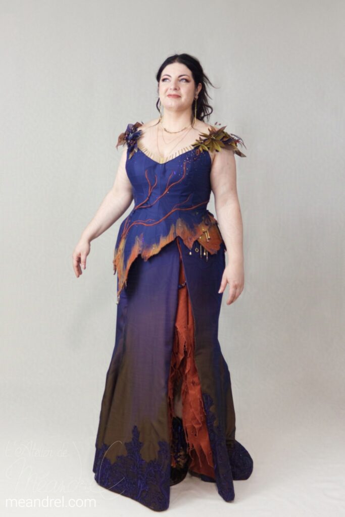 La même tenue de face ; on voit la forme "sirène" de la jupe qui est fendue sur le côté, et des décors de lianes qui grimpent sur le corsage.