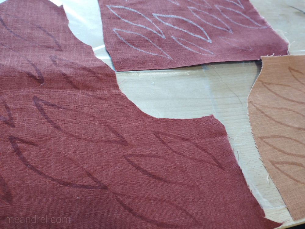 Tissu sur une table, avec des formes de feuilles brillantes (c'est les contours, encollés, pour que ça ne s'effiloche pas après découpe)