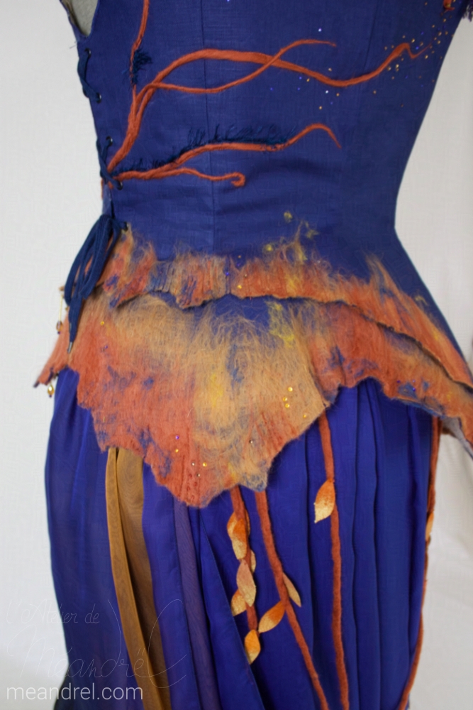Zoom sur le dos avec les belles couleurs dégradés de la laine rousse et rouille sur fond bleu.