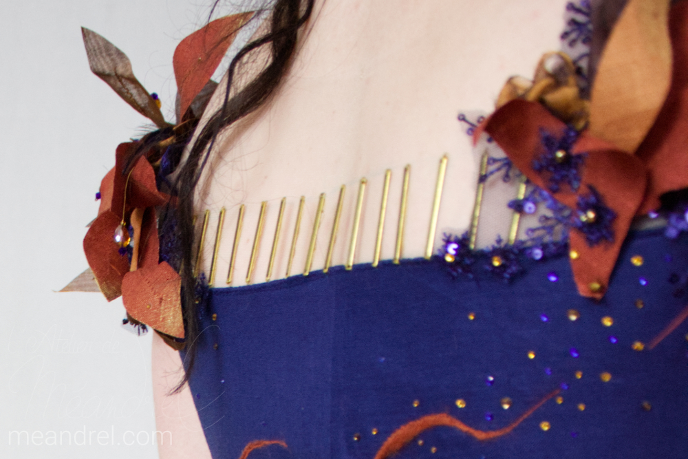 Vue du dos, dont le décolleté est relevé de petites barrettes verticales en laiton.